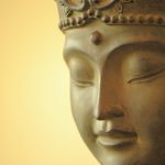 A close up view of the face of a Buddha statue on a magnolia background